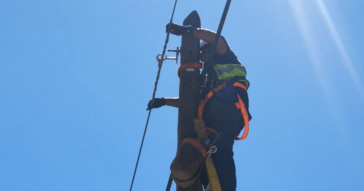 Instalación en campo de un clamp de suspensión en poste de red FTTH aérea, técnico trabajando en altura, Monstertek Perú