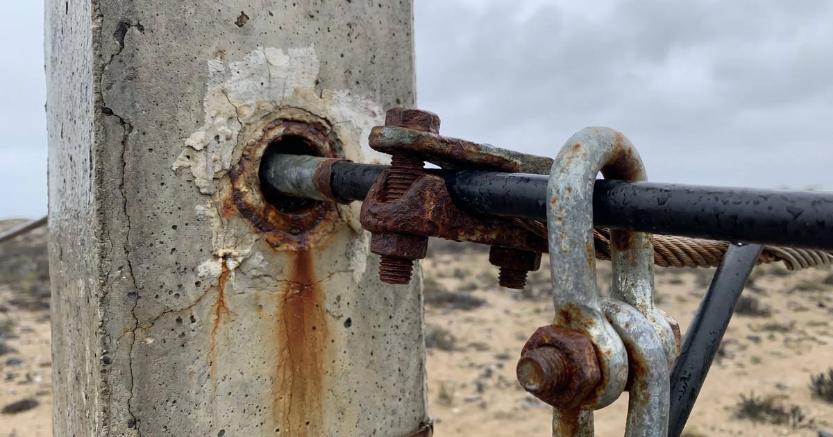 Herraje de acero corroído y oxidado instalado en poste de concreto en ambiente costero húmedo del Perú, Monstertek